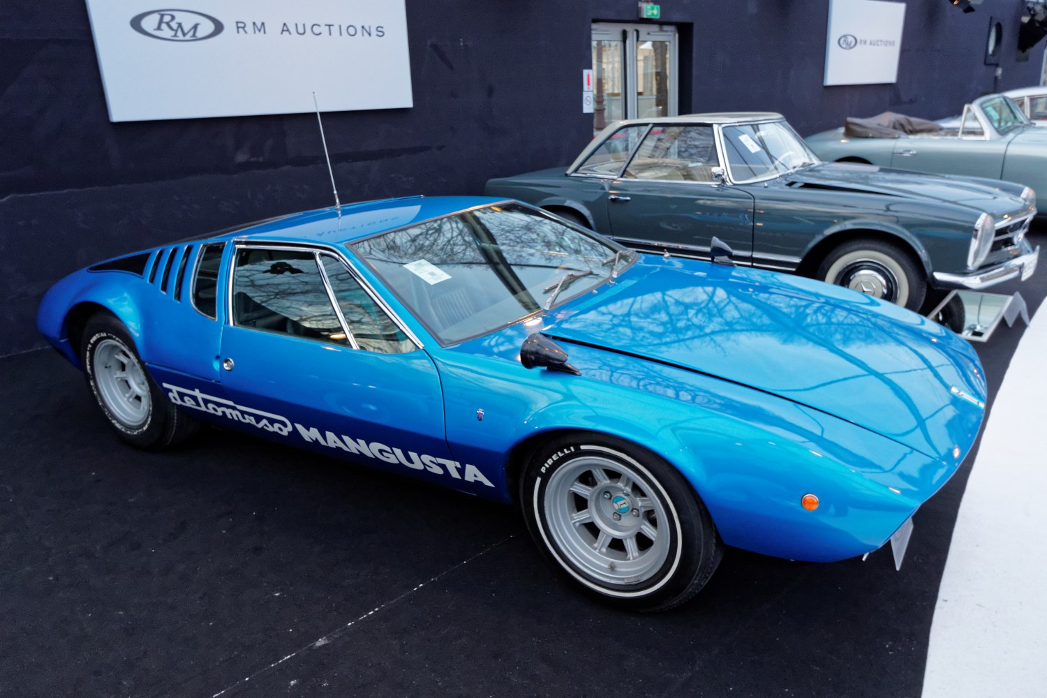 Blue mid-engine sports coupe with side vents and bold white branding