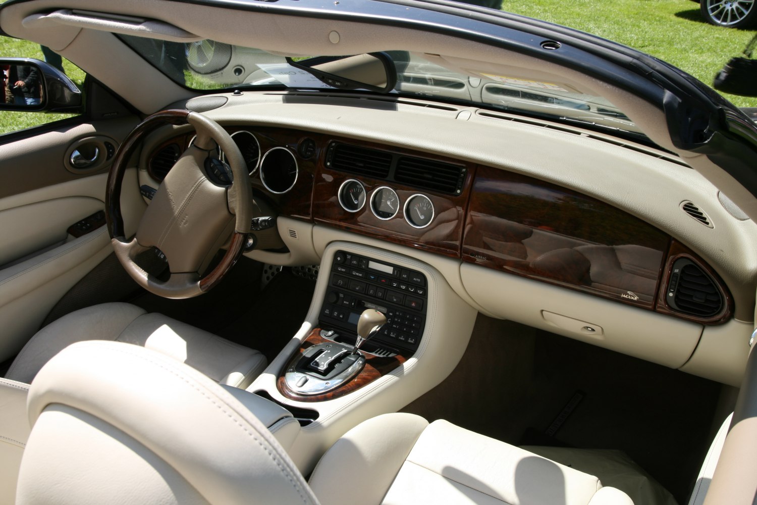 Luxury beige leather interior with wood trim dashboard and automatic gear shift