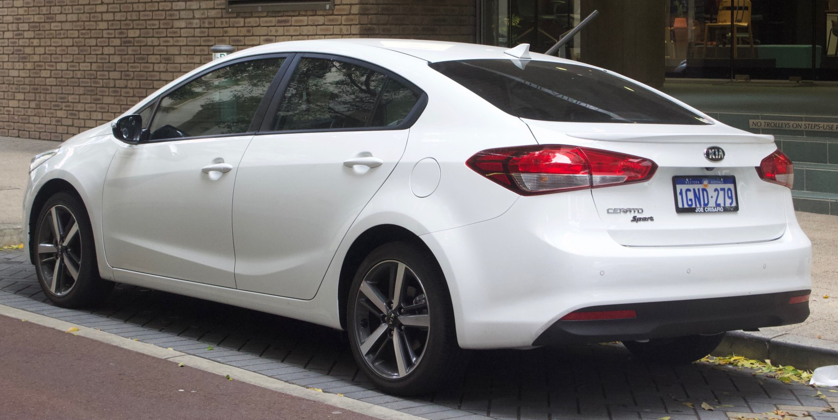Rear and side view of a white compact sedan with sport wheels
