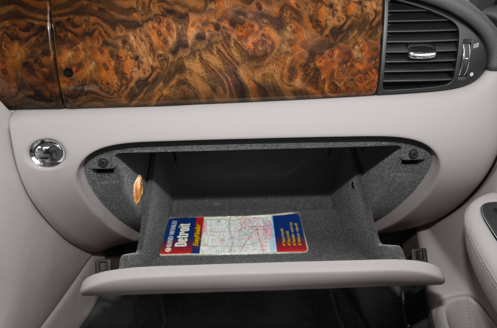 Open glove compartment with wood trim and plush interior.