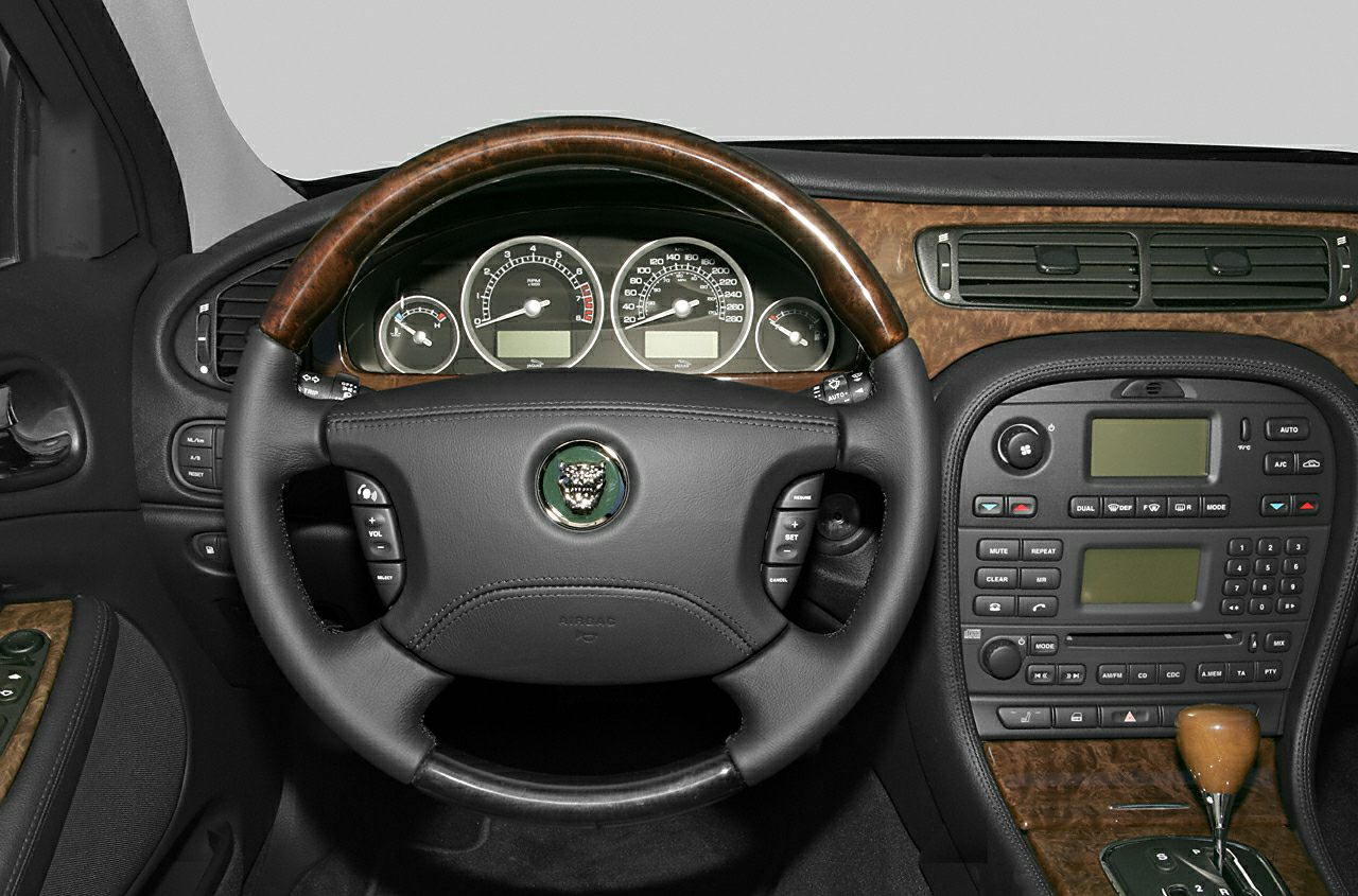 Wood-trimmed steering wheel and detailed dashboard with multiple gauges and controls