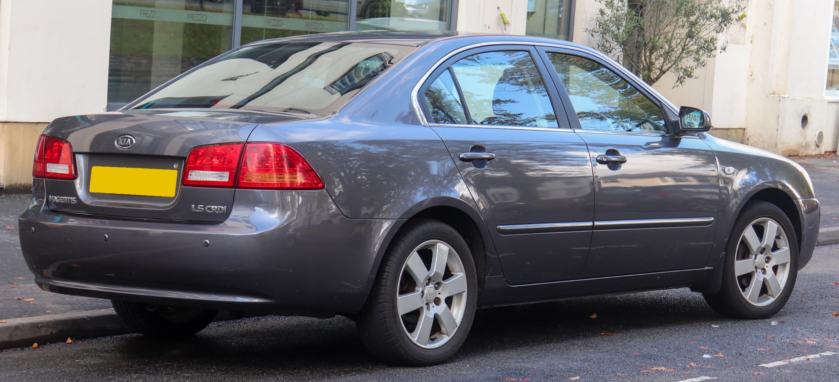 Rear side profile of sedan with alloy wheels and metallic grey paint