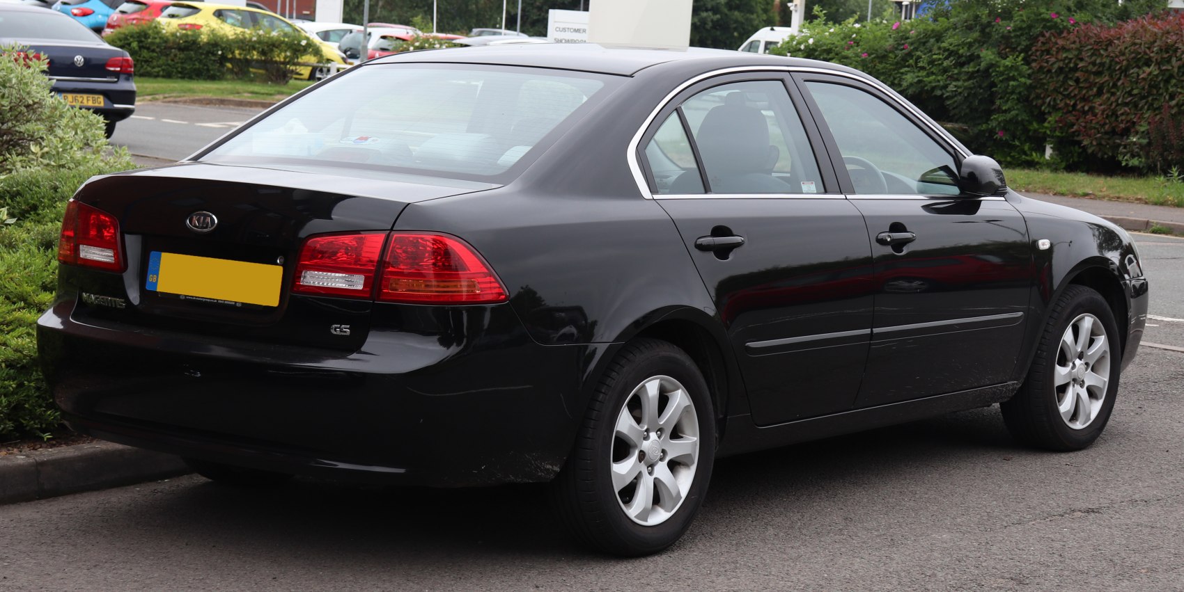 Rear and side profile of a black mid-size sedan with alloy wheels and clear tail lights