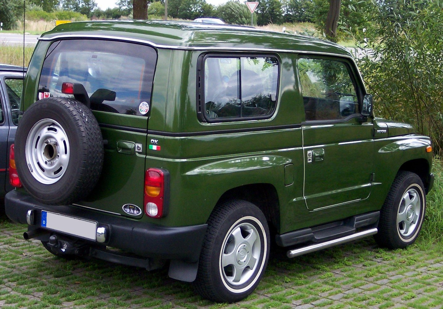 Green boxy SUV with rear spare tire and unique rear windows