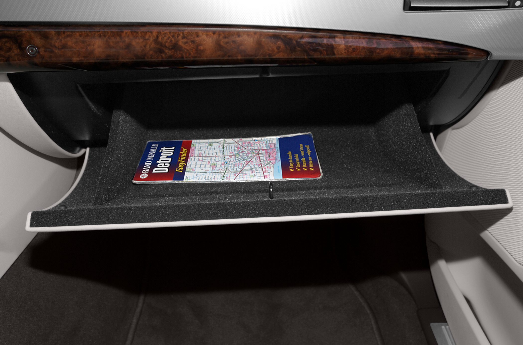 Open glove compartment with wood trim and map inside