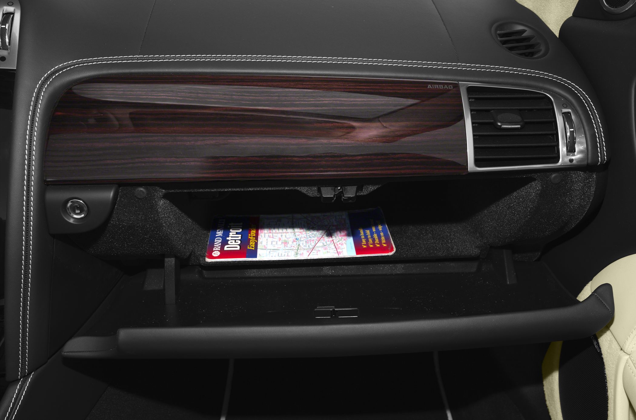 Open glove compartment and wooden dashboard trim with stitched leather