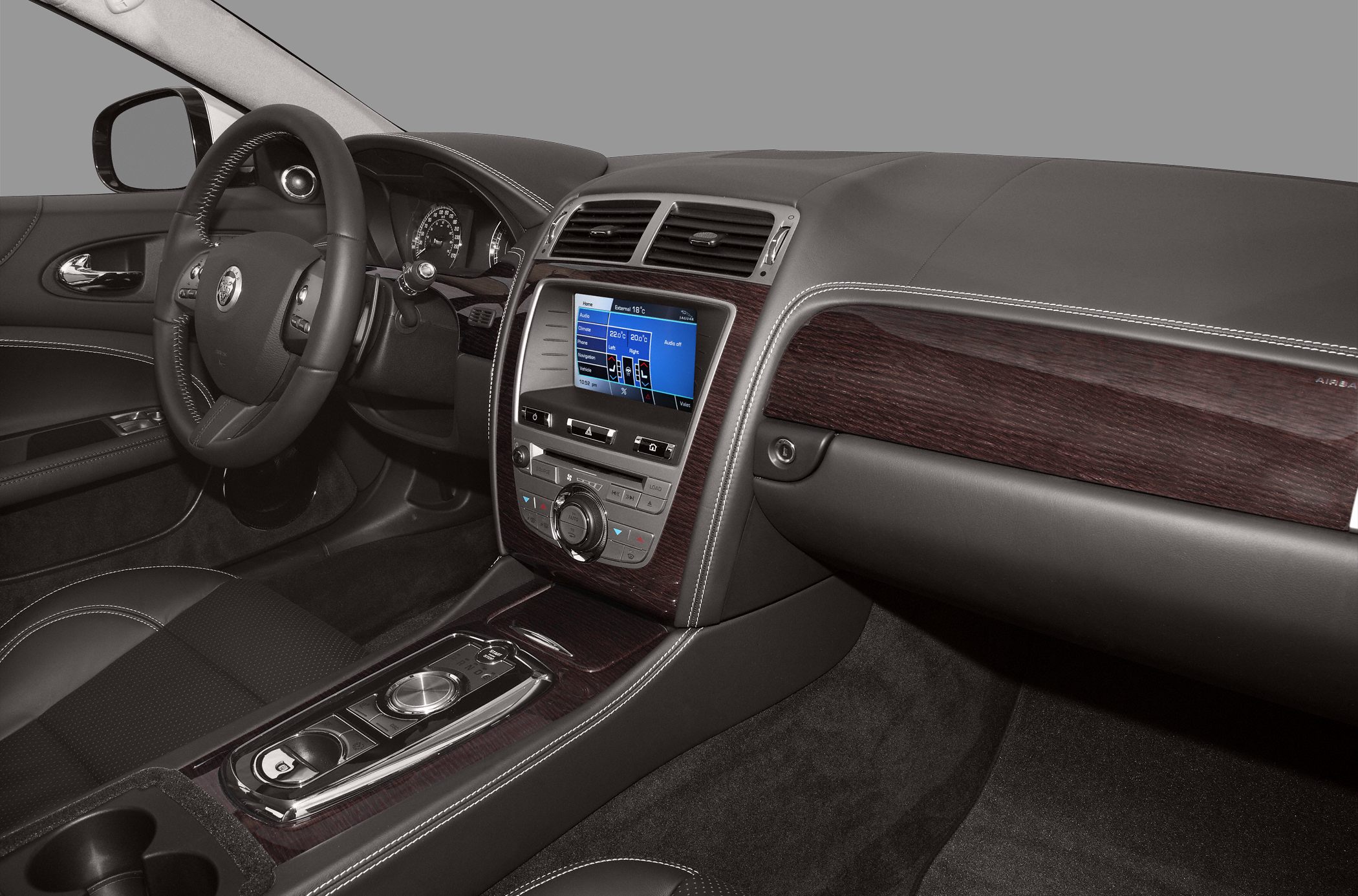 Steering wheel, infotainment screen, wood-trimmed dashboard, center console controls