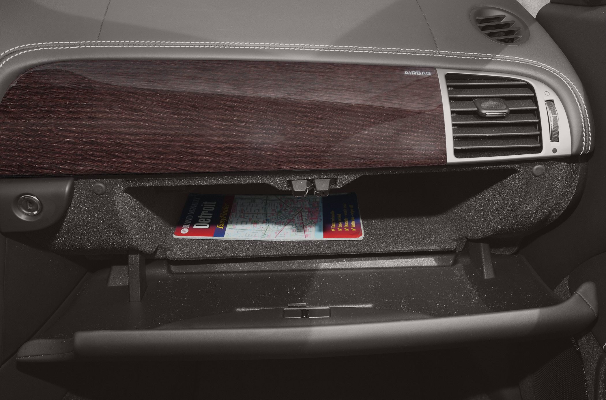 Glove compartment with wood trim and air vent in car interior