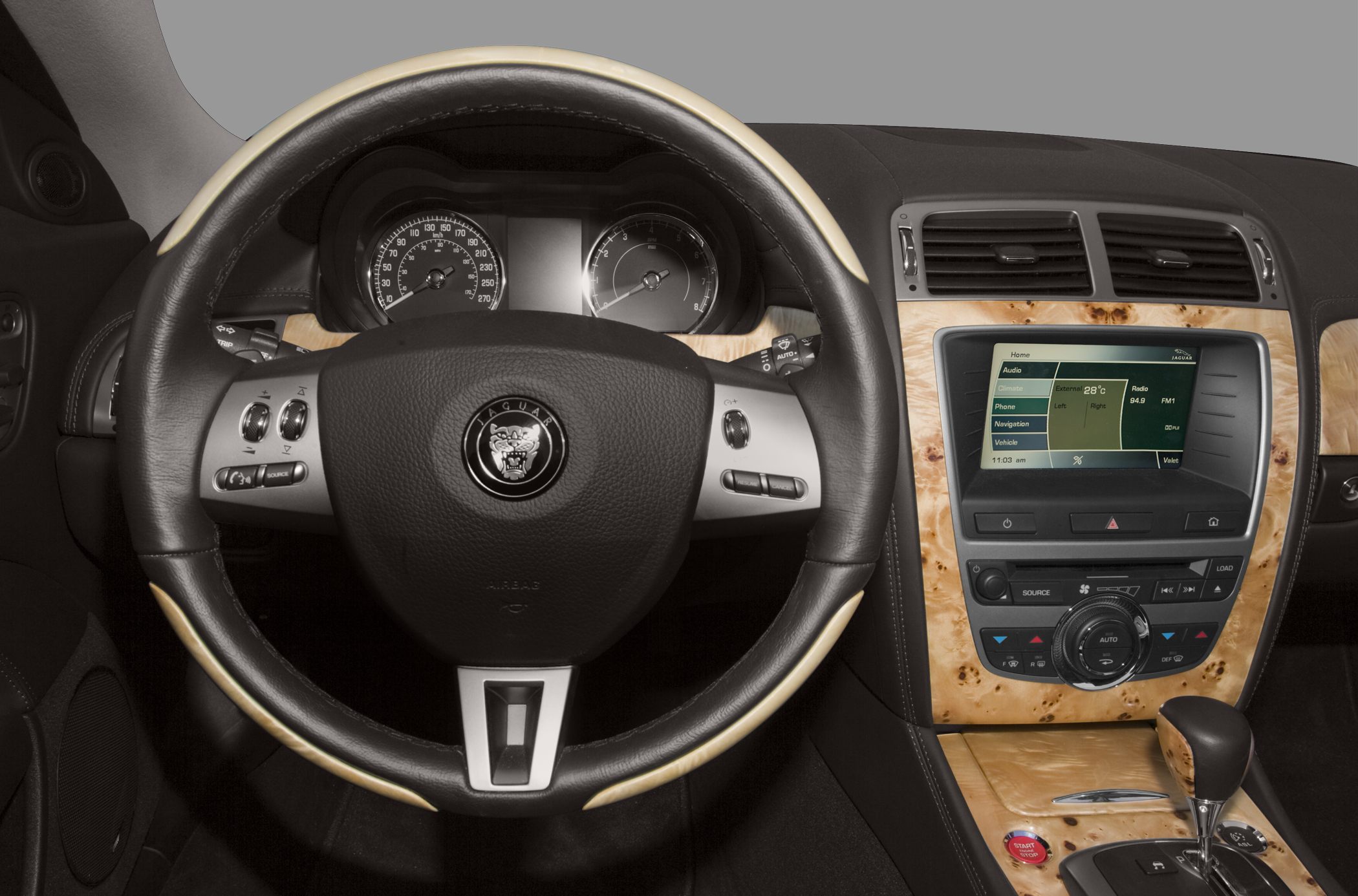 Steering wheel with Jaguar logo and wood-trimmed dashboard with infotainment controls