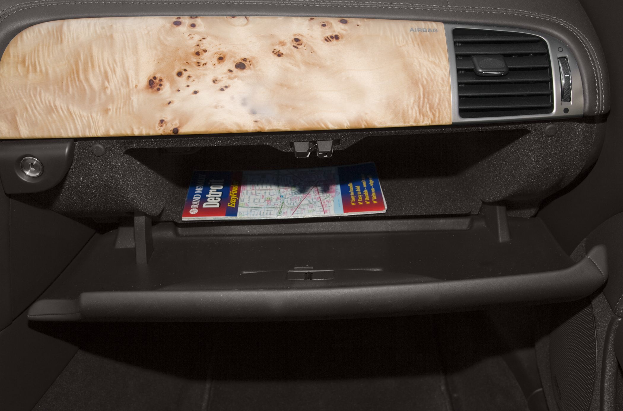 Open glovebox with map and wood trim dashboard