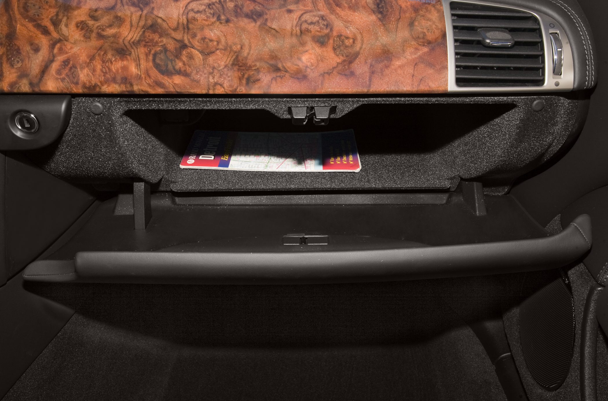 Open glove compartment with wood trim dashboard and air vent