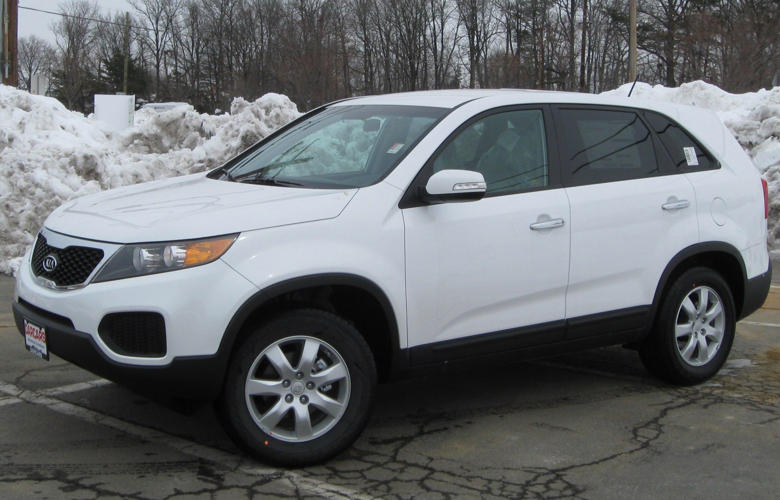 White mid-size SUV front-side view with alloy wheels parked near snow