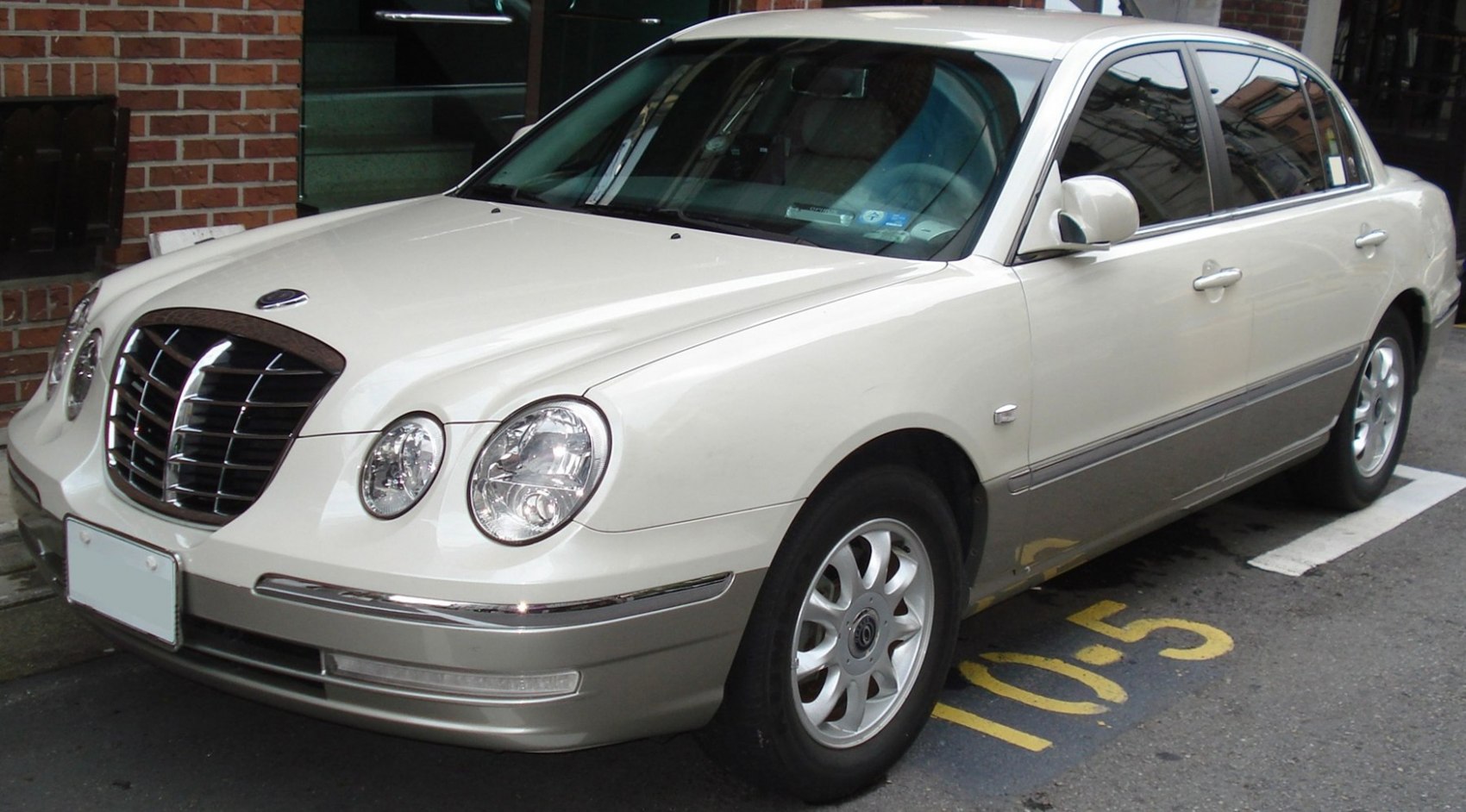 White luxury sedan with rounded dual headlights and vertical slat grille.