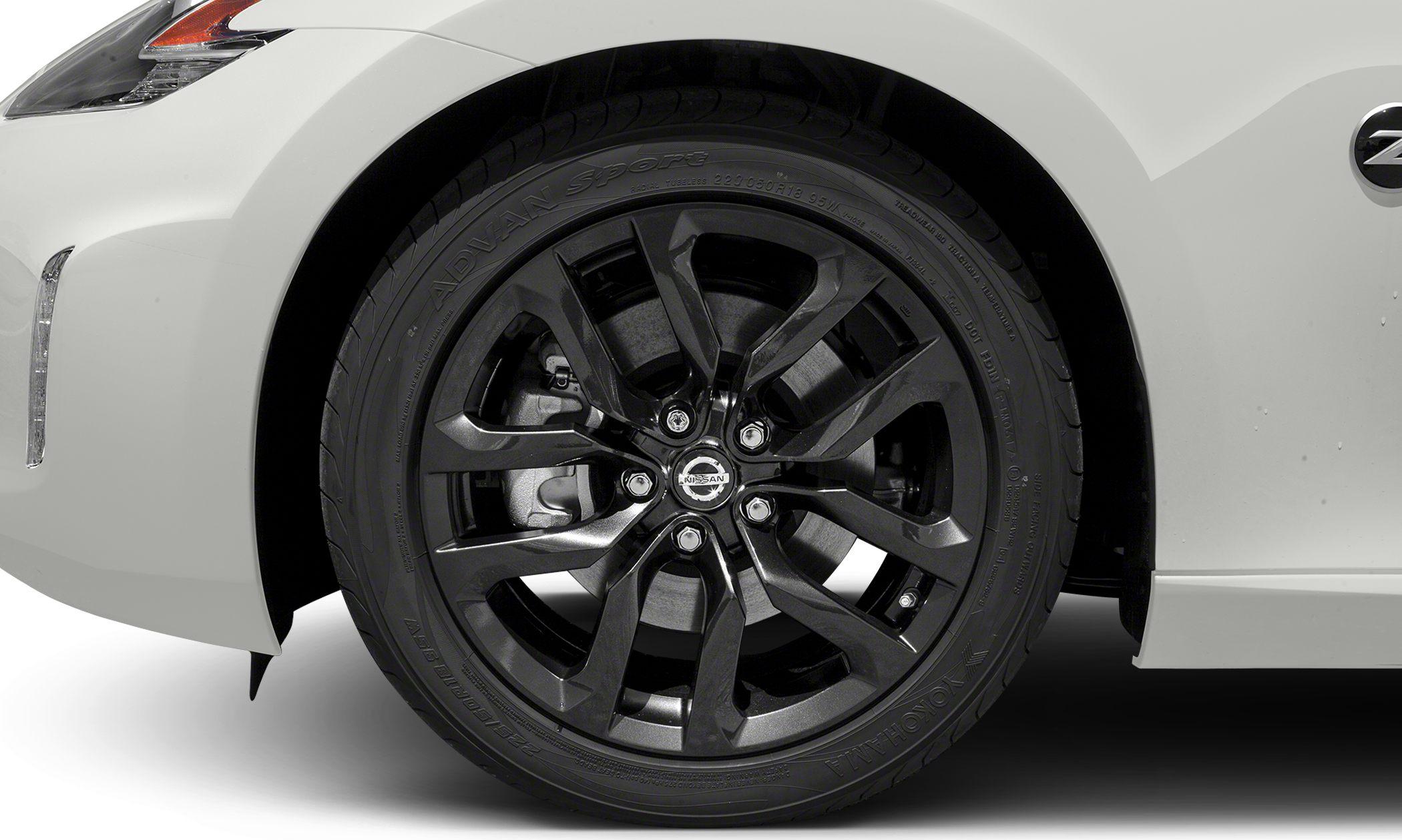 Black multi-spoke alloy wheel with visible brake components on a white body panel.