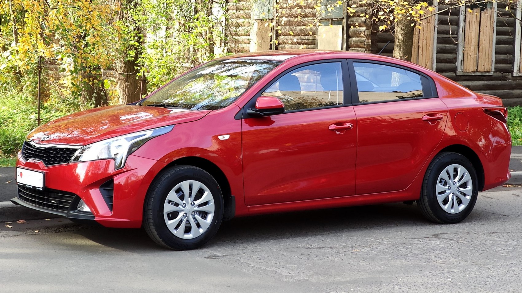 Red compact sedan with modern headlights and alloy wheels