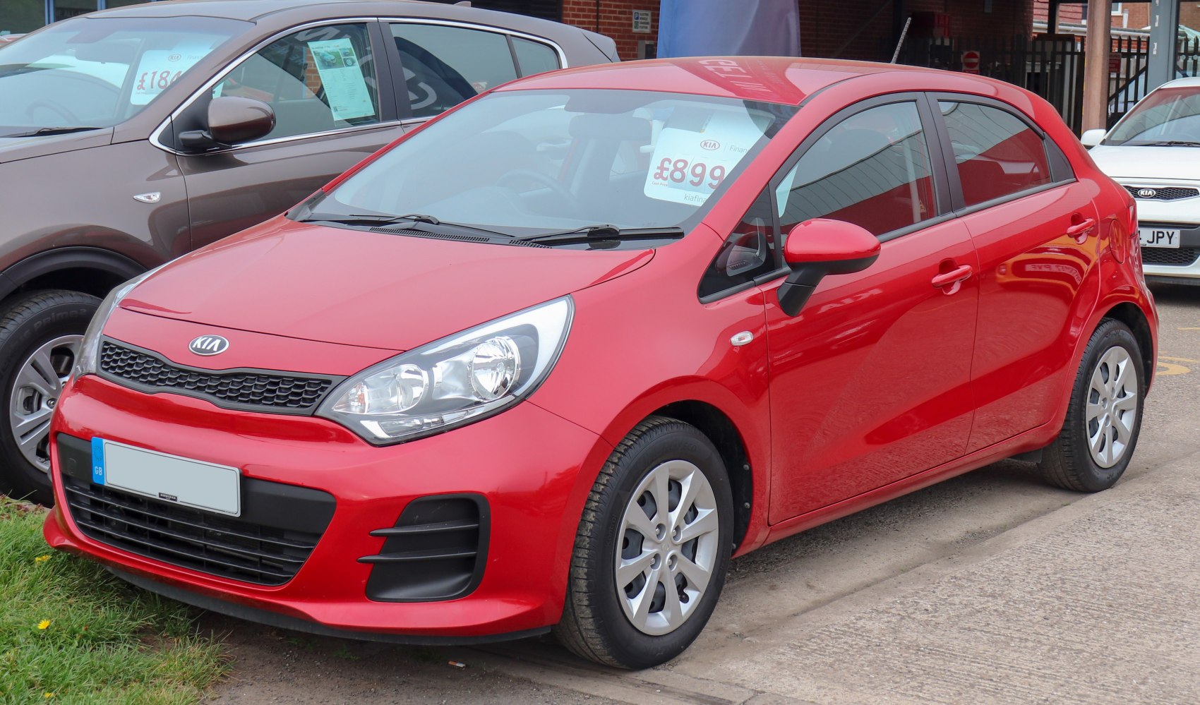 Red compact hatchback with front grille and headlight design