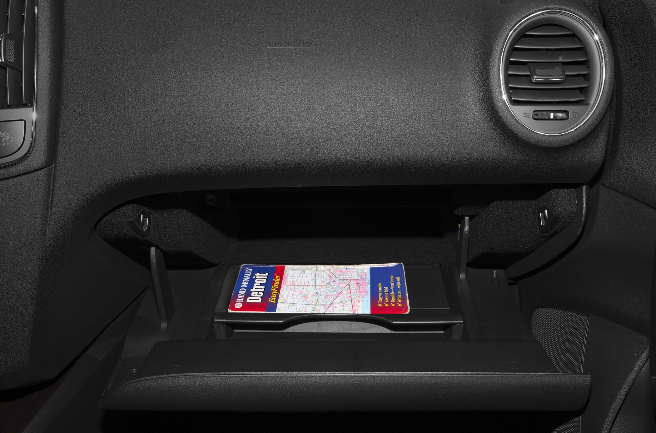 Open glove compartment and circular air vent on textured dashboard