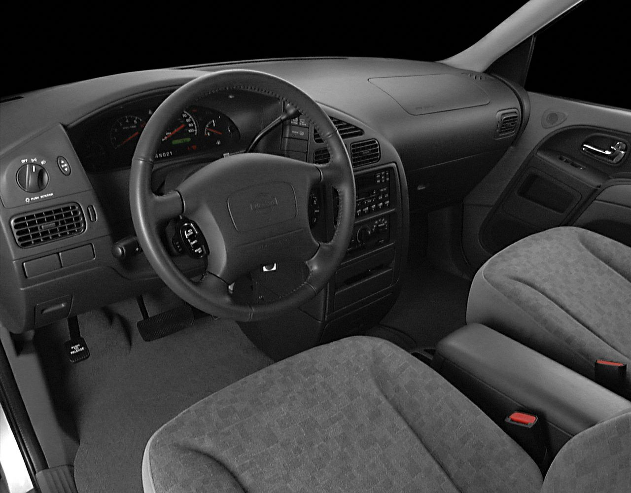 Dashboard, steering wheel, and front seats in 1990s minivan interior