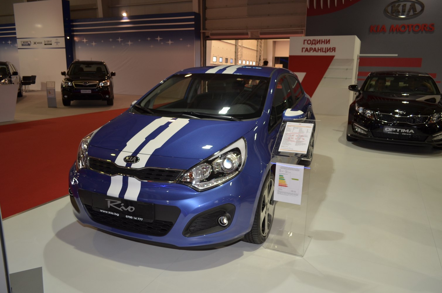Blue hatchback with white racing stripes and modern headlamps