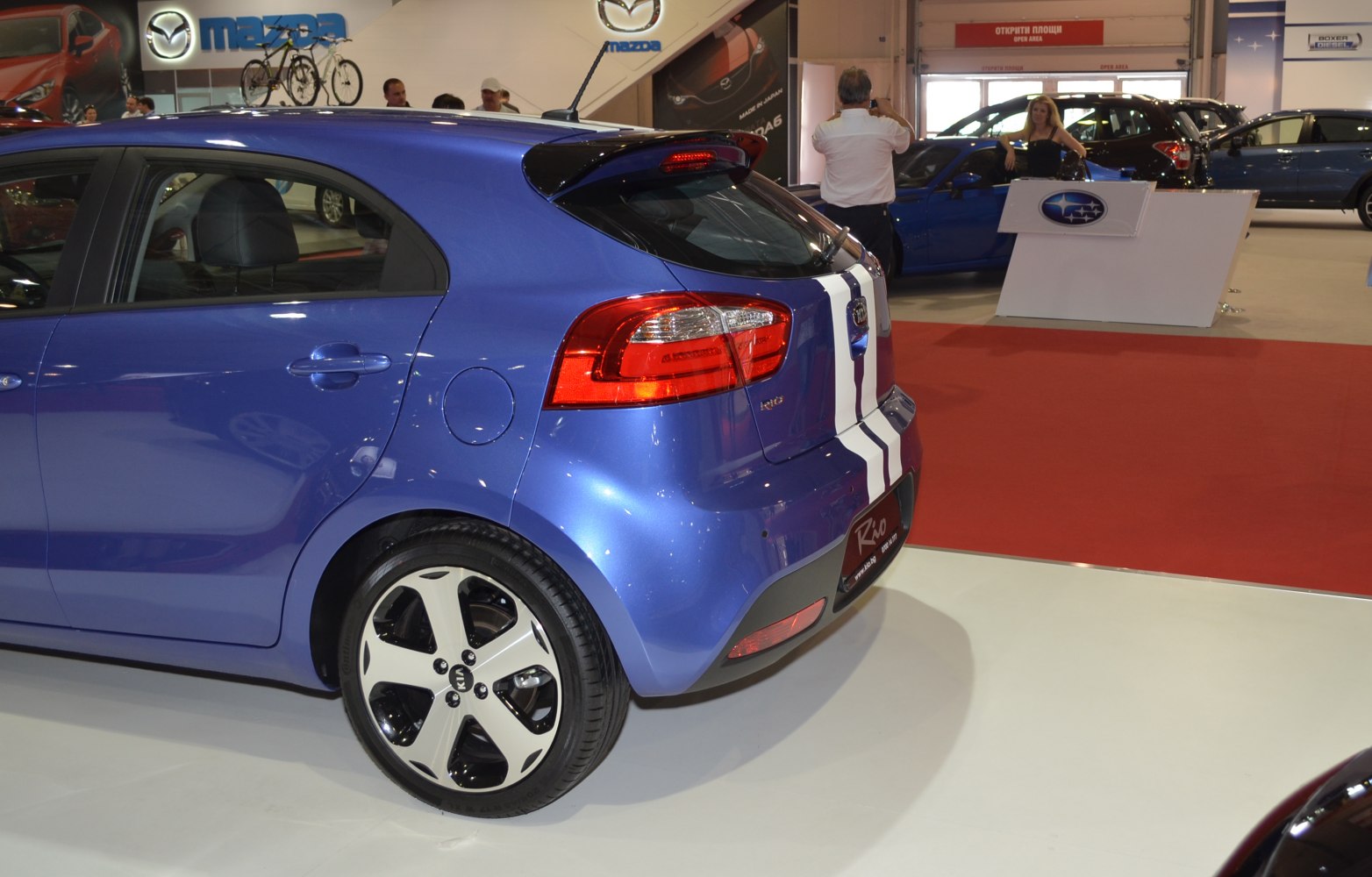 Blue hatchback rear with white racing stripes and distinctive taillights