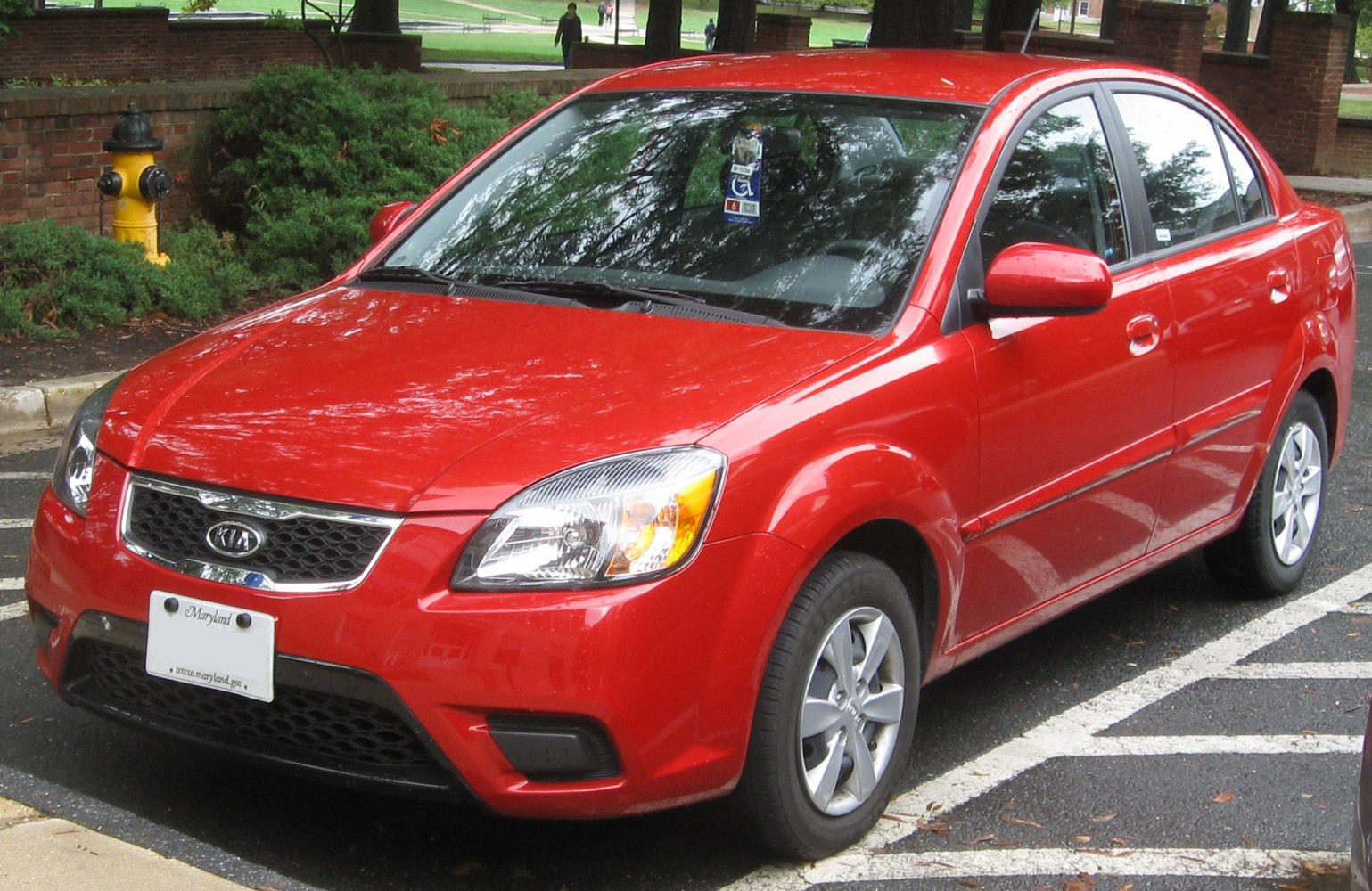Red compact sedan with facelift grille and alloy wheels