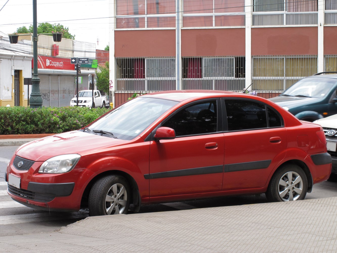 Red four-door sedan with alloy wheels and black side trims