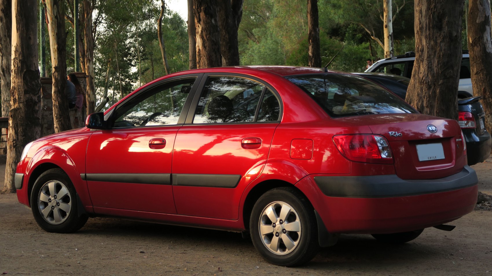 Rear side view of red compact sedan with visible taillights and fuel cap