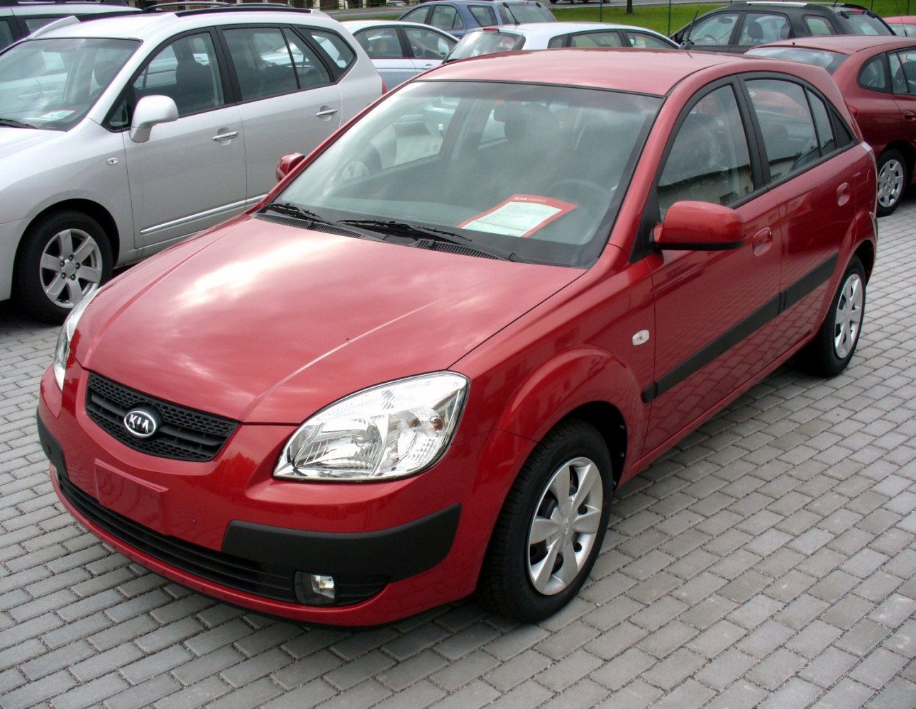 Red hatchback with black side trim and alloy wheels parked on pavement