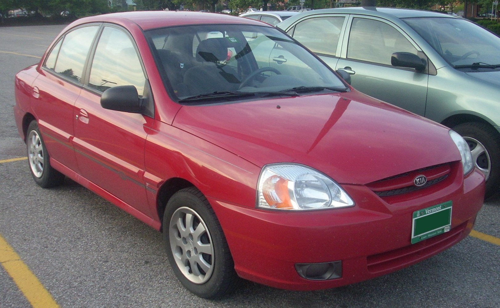 Front and side view of a compact red sedan with distinctive headlights and clean lines