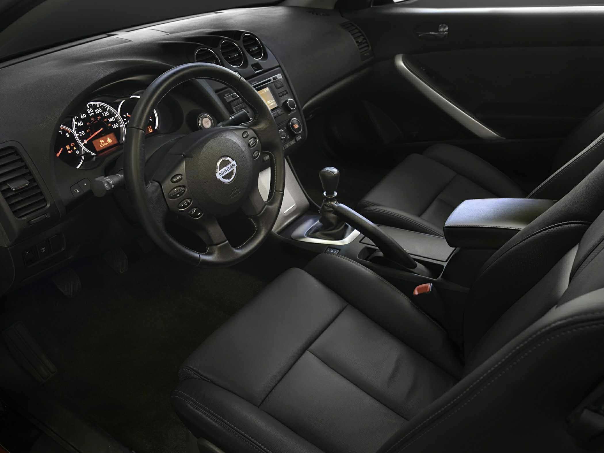 Manual gearshift, leather seats, and dashboard controls in car interior