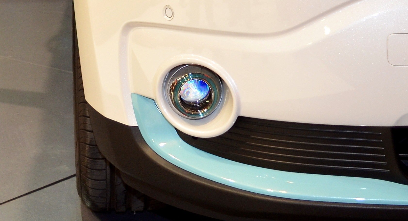 Close-up of front fog light and bumper on white vehicle
