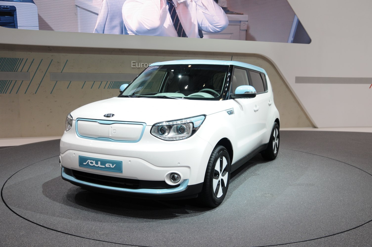 Front-side view of a white electric compact vehicle with distinctive headlights and smooth contours.