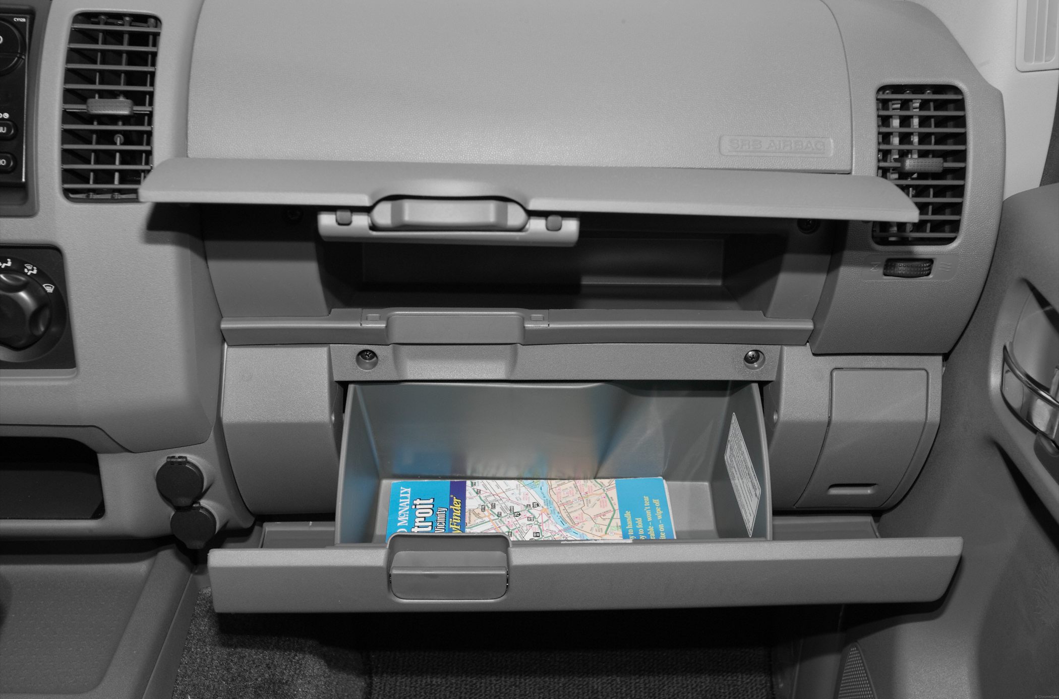 Open glove compartments in vehicle dashboard with map inside.