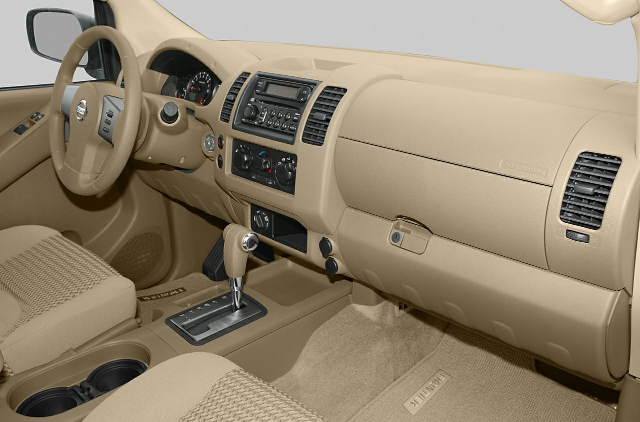 Beige car interior with dashboard, automatic gear shift, and air vents.