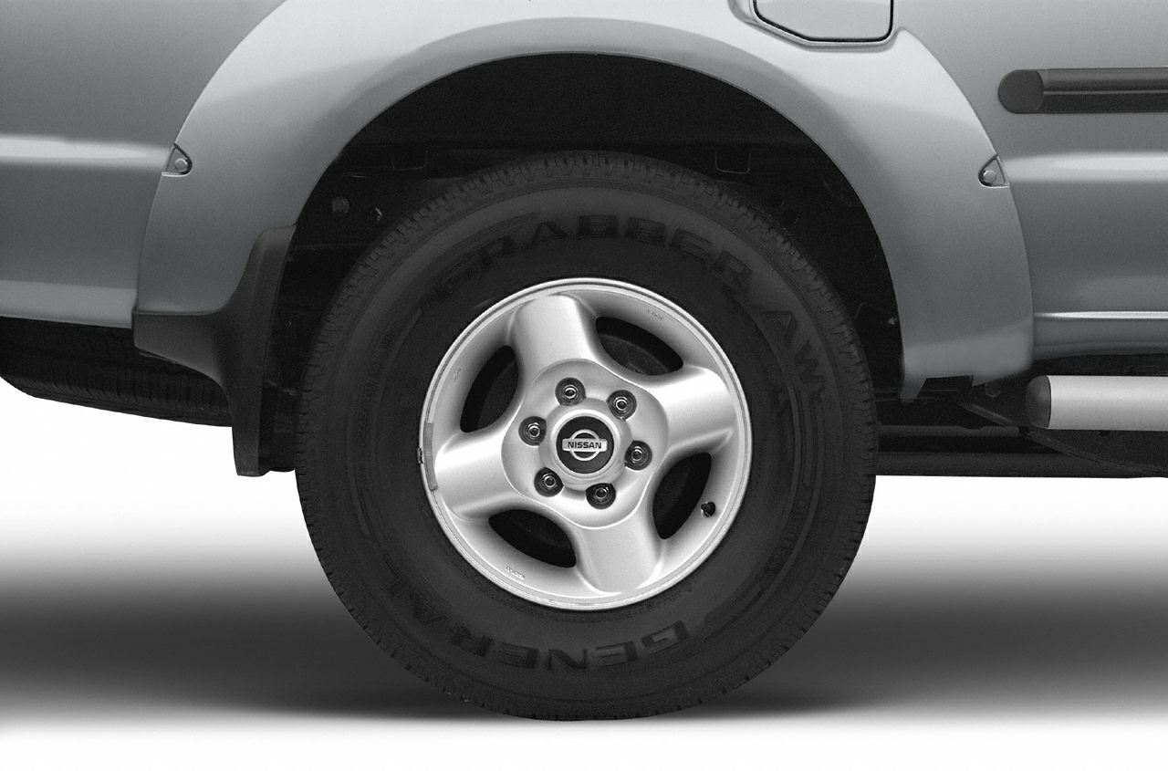 Close-up of five-spoke alloy wheel with off-road tire on pickup rear fender.
