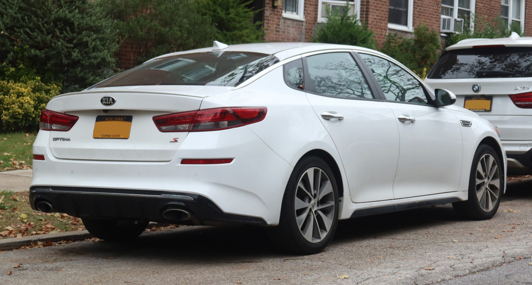 Rear view of a white sedan showcasing tail lights and dual exhaust system