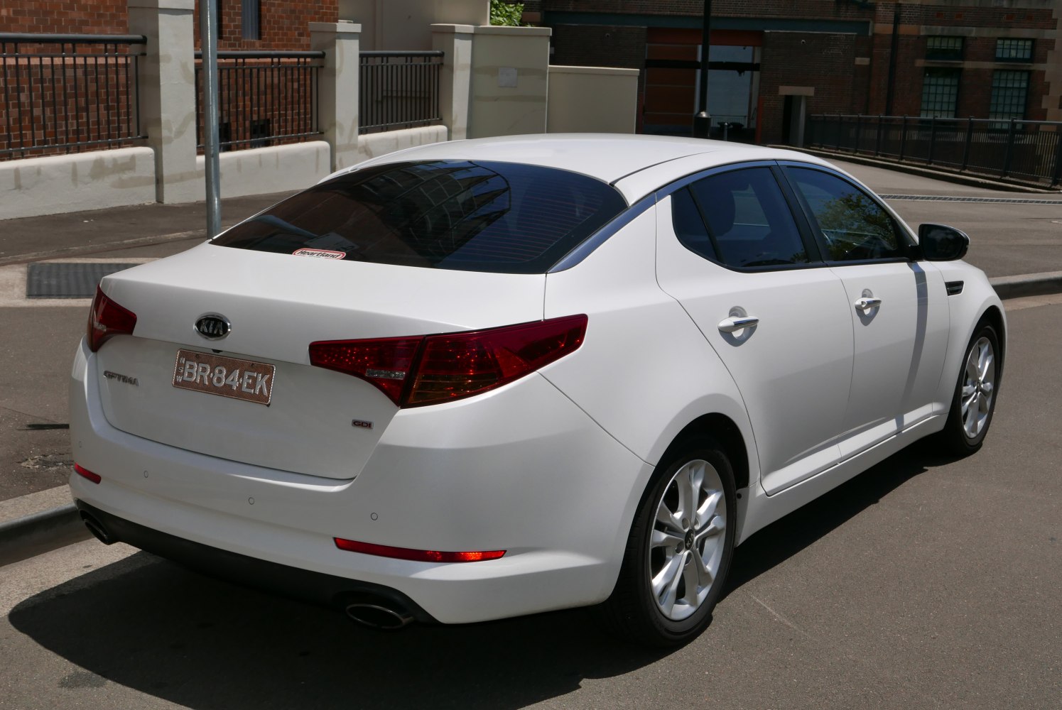 White sedan with sharp tail lights and alloy wheels from rear side.