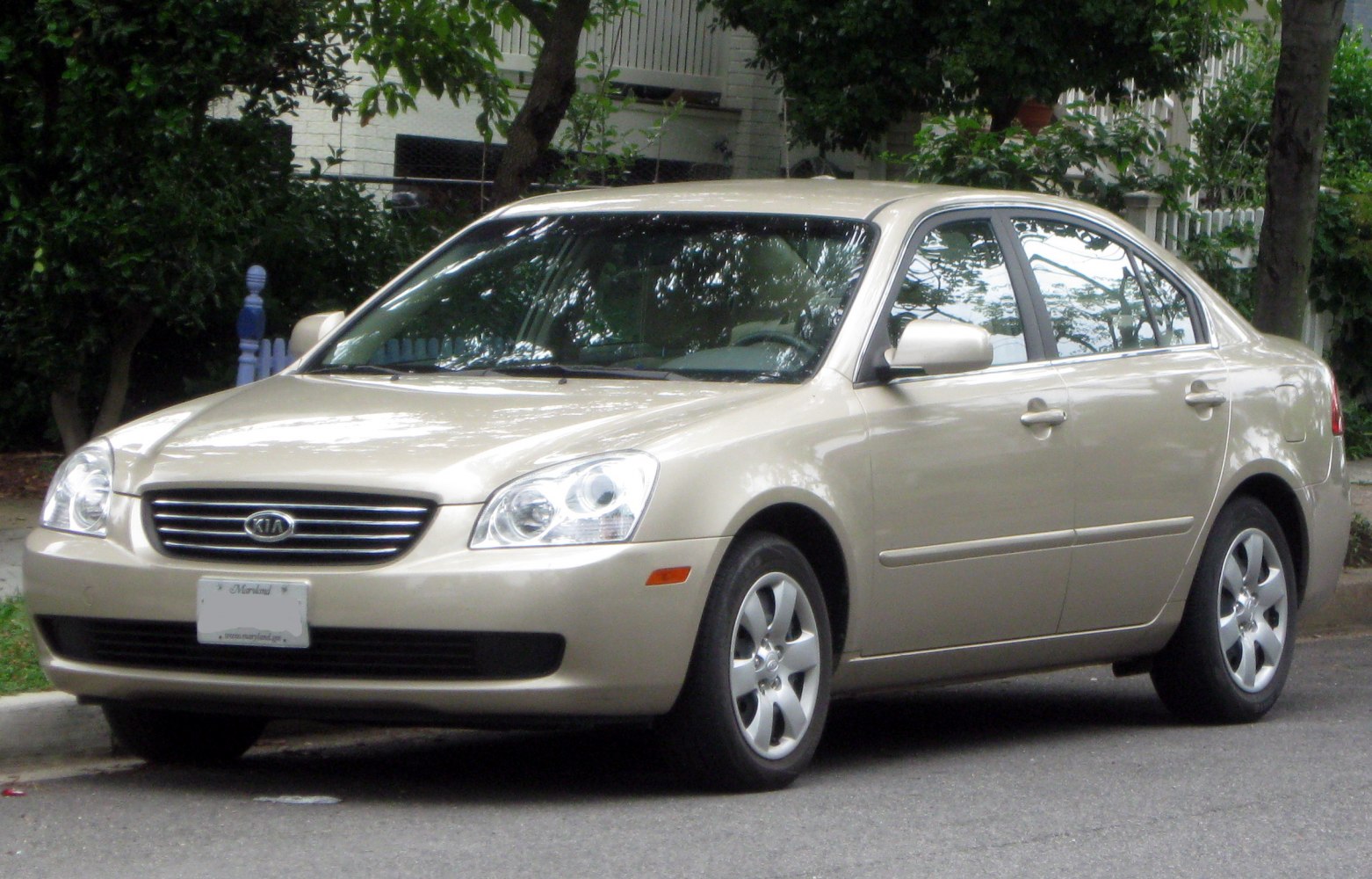 Front side view of a mid-2000s beige sedan with smooth lines and distinct headlights