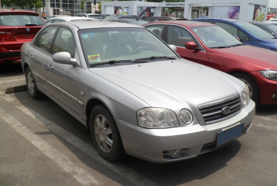 Silver sedan with dual headlights and horizontal grille in parking lot.