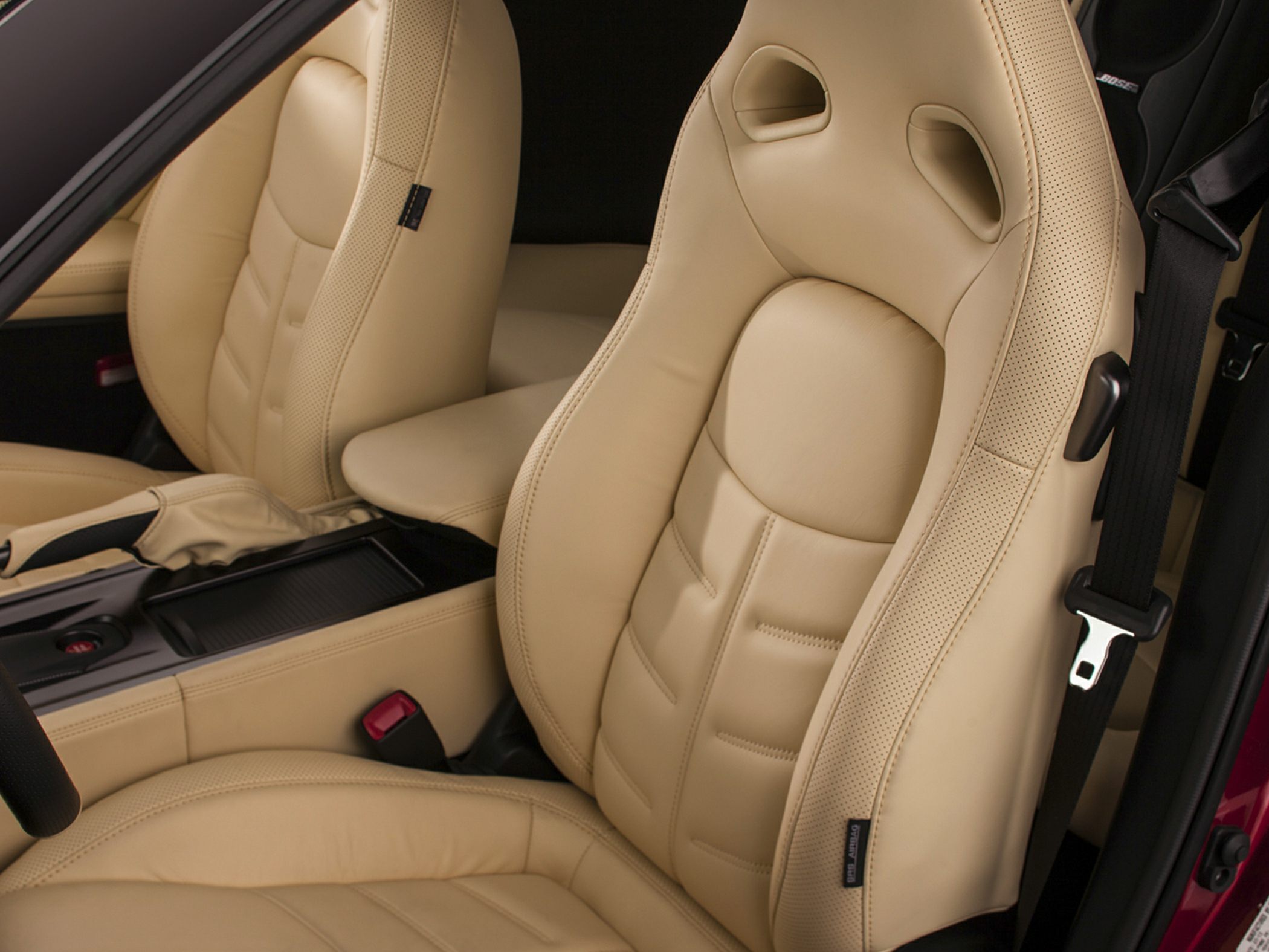 Beige leather sports seats with integrated headrests and perforated bolsters.