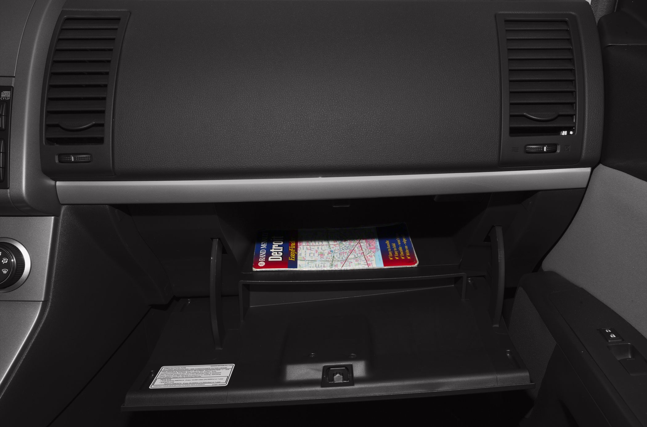 Open glove box with ventilation vents and a map inside