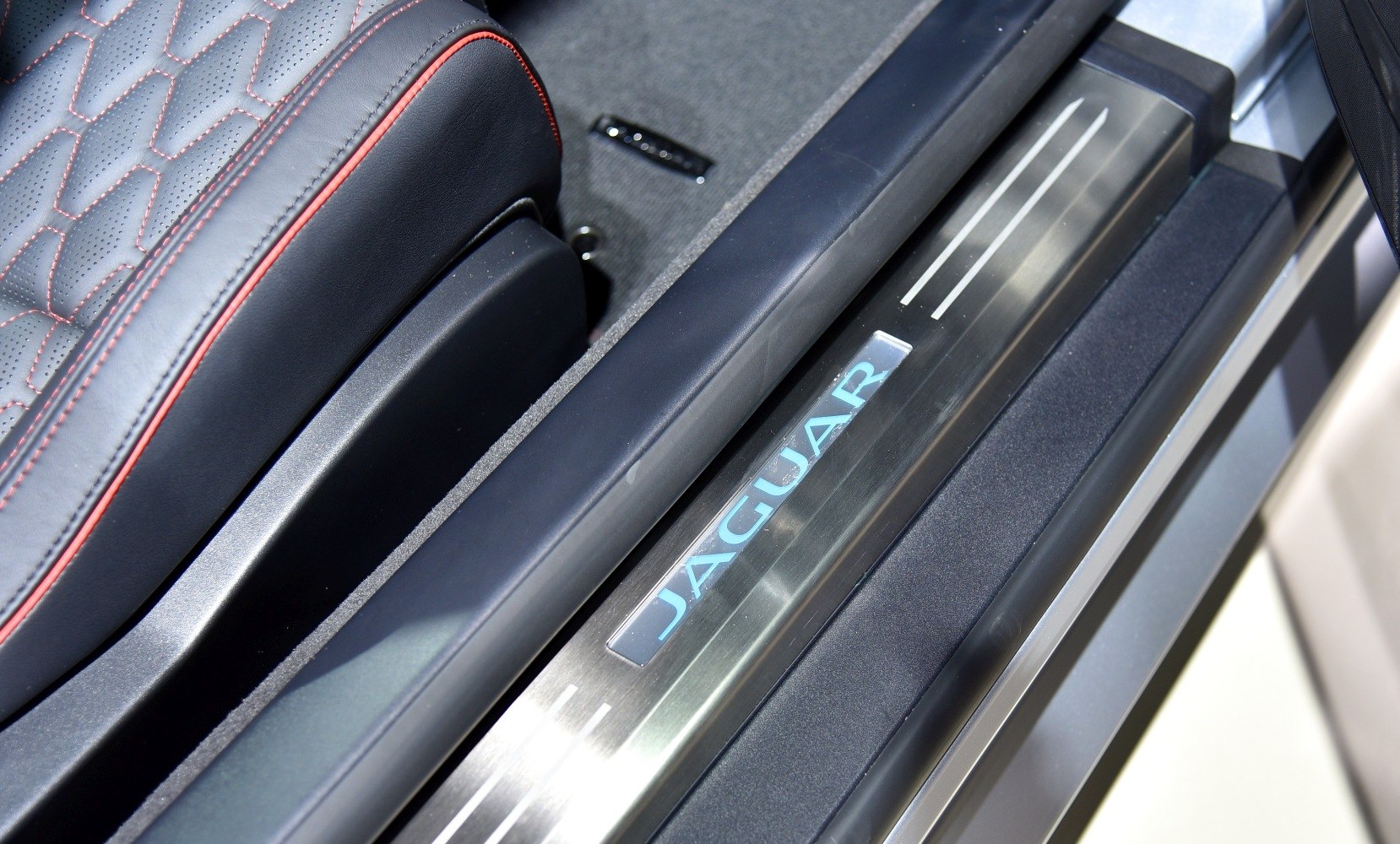Illuminated Jaguar door sill and leather seat with red stitching