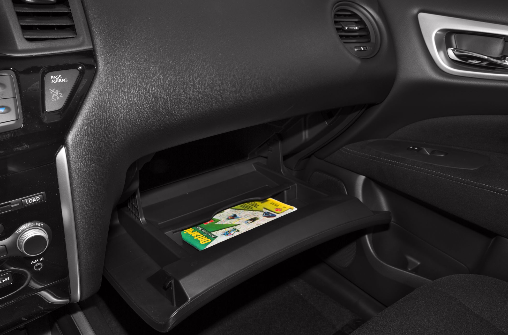 Open glove compartment with storage space containing a map