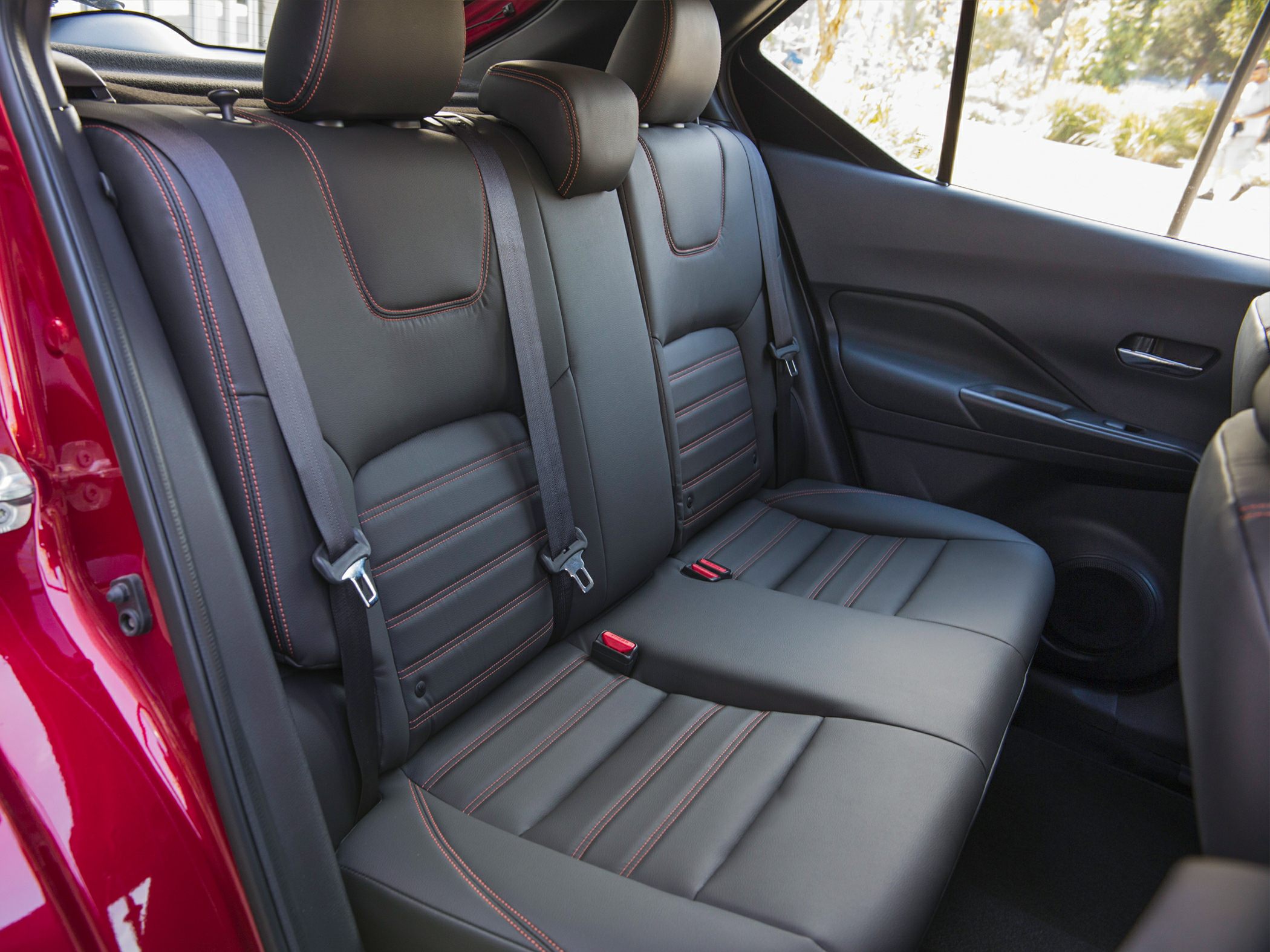 Rear black leather seats with red stitching and headrests.