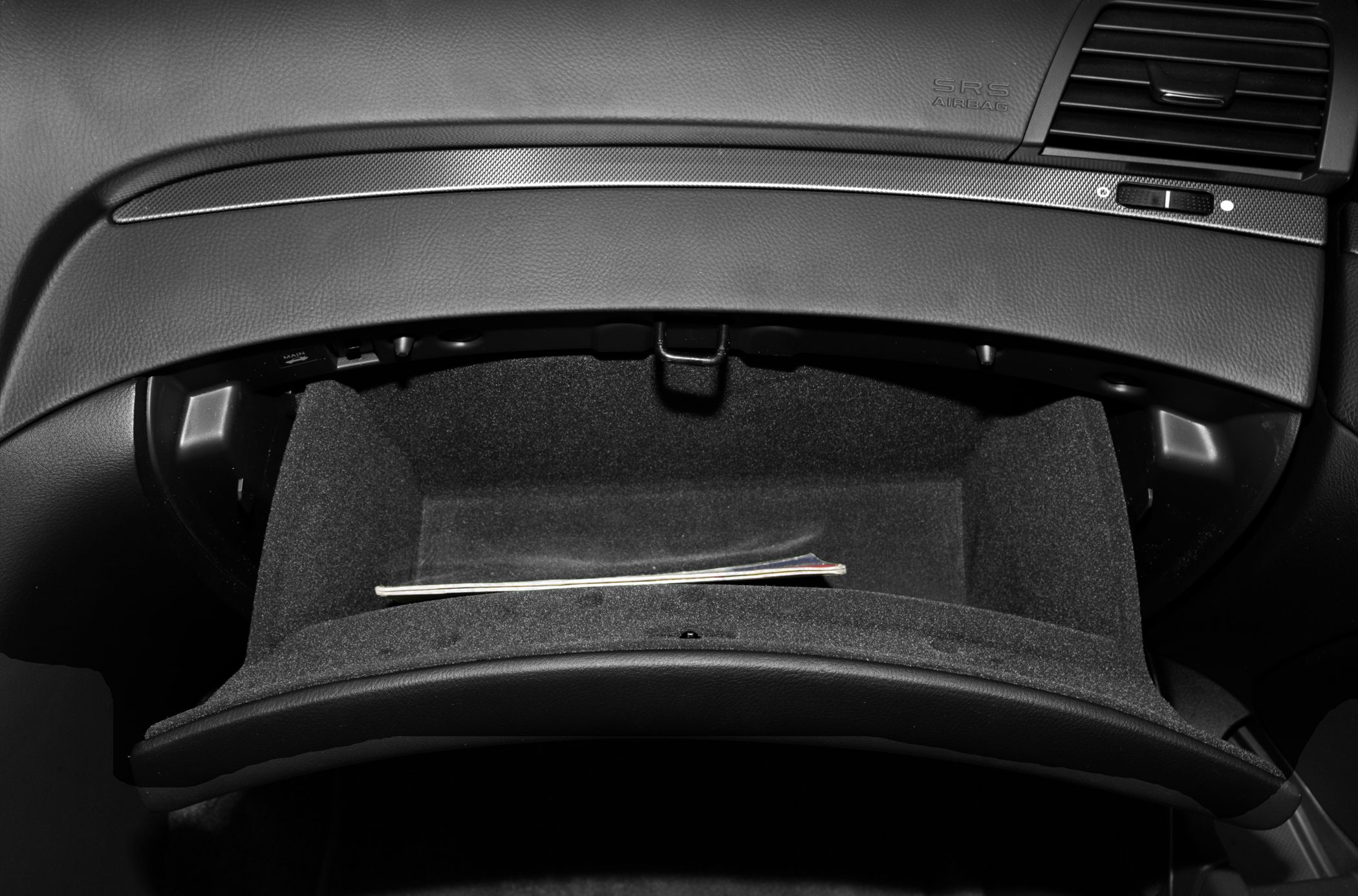 Open glove compartment with textured dashboard and airbag label.