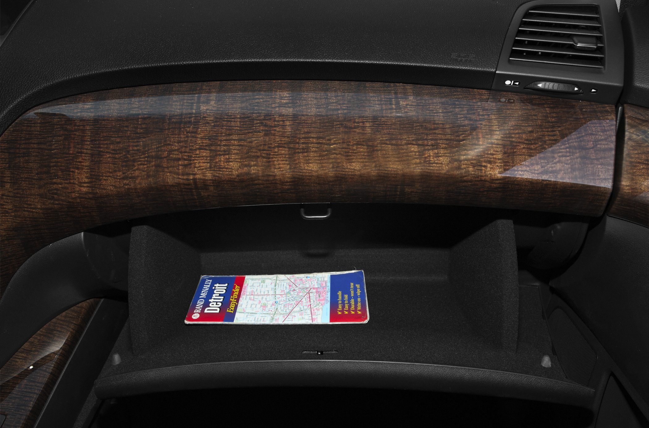 Luxury wood grain dashboard trim and open glove compartment with map.