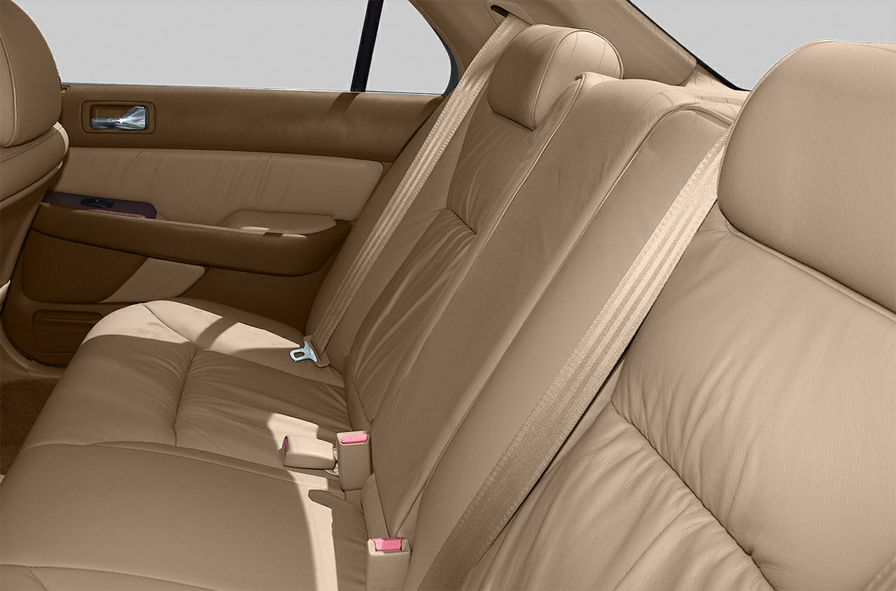 Rear seat with beige leather upholstery and seat belts.