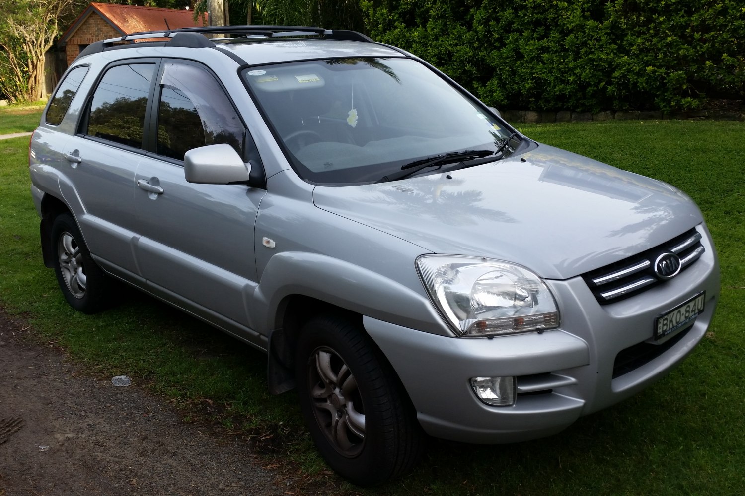 Front and side view of silver SUV showing grille, headlights, roof racks.