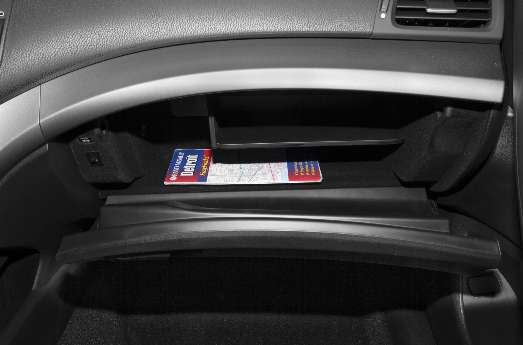 Open glovebox with a roadside map inside on car dashboard
