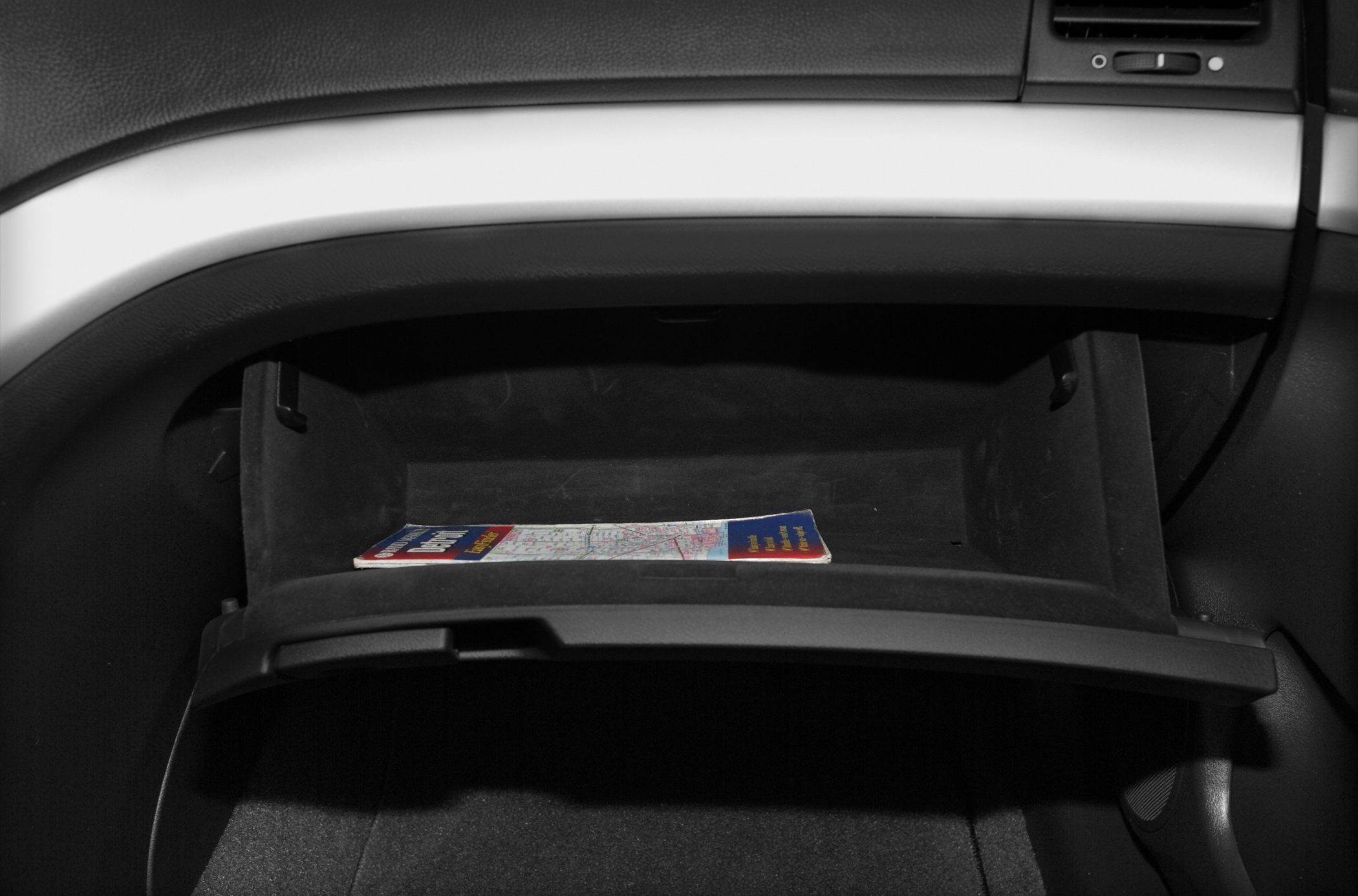 Open glove box with a folded map inside, showing storage space and design.